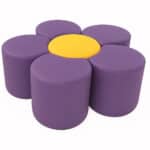 Puf redondo con diseño en forma de flor margarita, usado como asiento decorativo.”